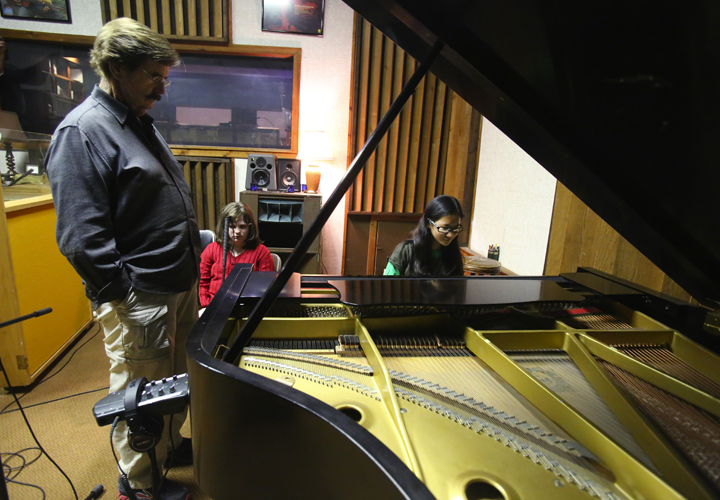 Gabriella Orton playing the piano at Fame Studios with Rick Hall looking on.